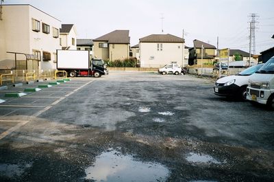 Vehicles on road by buildings in city against sky