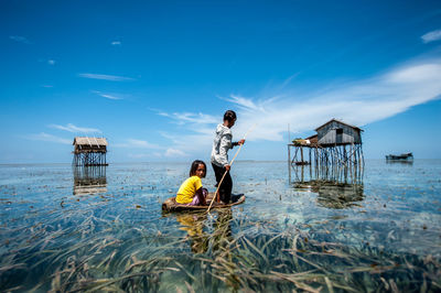 People sitting in sea against sky