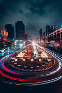 Illuminated railroad tracks in city against sky at night