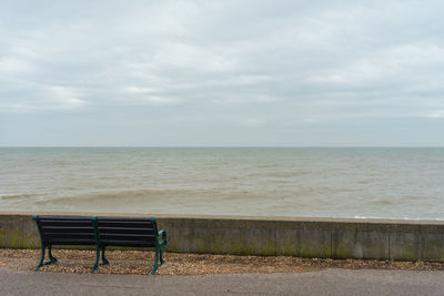 Empty chair on beach against sky