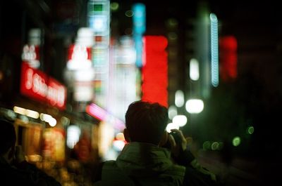 Rear view of man on illuminated street at night