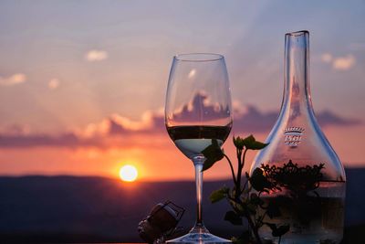 Close-up of beer bottle against sea during sunset