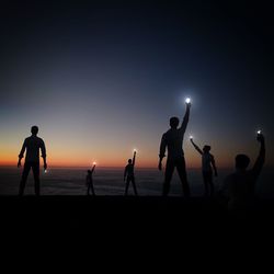 Silhouette people on beach against sky during sunset