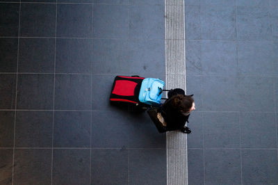 Directly above shot of woman walking with luggage on walkway