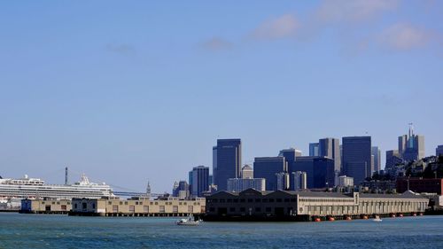 River by cityscape against blue sky