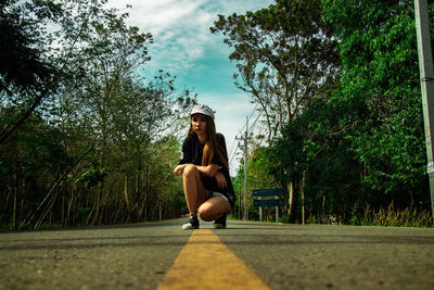 Full length of woman sitting in park against sky