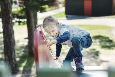 Happy girl climbing slide at yard