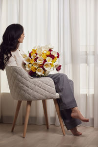 Portrait of woman with flowers on table at home