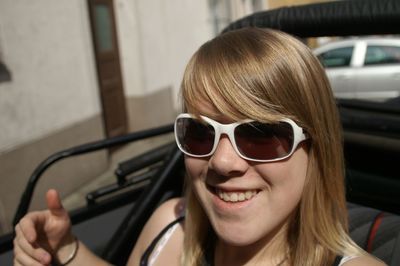 Portrait of smiling woman wearing sunglasses while sitting in car