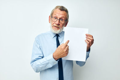 Portrait of businessman holding paper while standing against white background