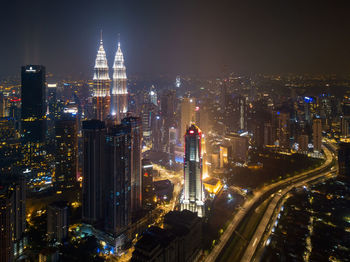 Illuminated road amidst buildings in city at night