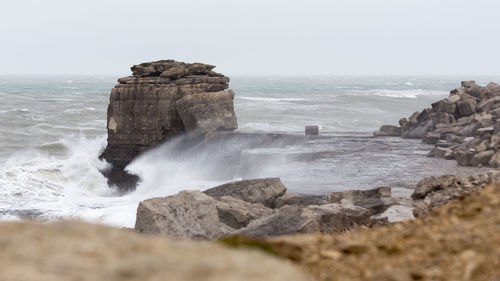 Scenic view of rocks in sea against clear sky