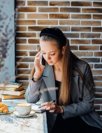 A beautiful young woman is talking on a mobile phone with friends or colleagues at a table in a cafe