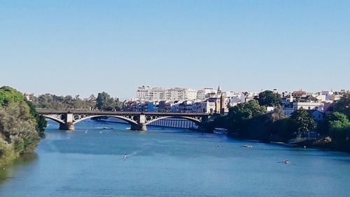 Bridge over river in city against clear sky