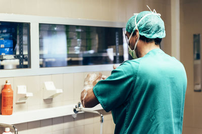 Rear view of man standing in bathroom