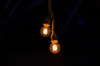 Low angle view of illuminated light bulbs in the dark