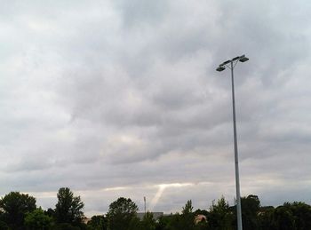 Low angle view of electricity pylon against cloudy sky