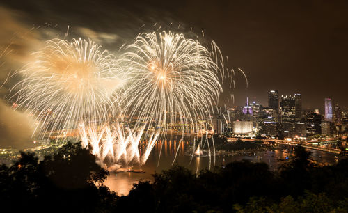 Firework display in city against sky at night