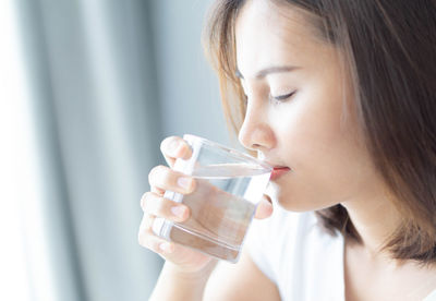 Close-up portrait of a young woman drinking glass