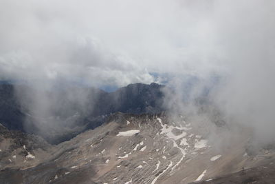 Clouds emitting from volcanic landscape against sky