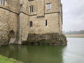 Old building by river against sky