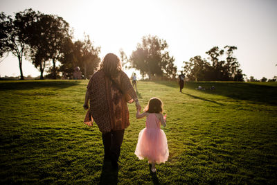 Rear view of women walking on grassy field