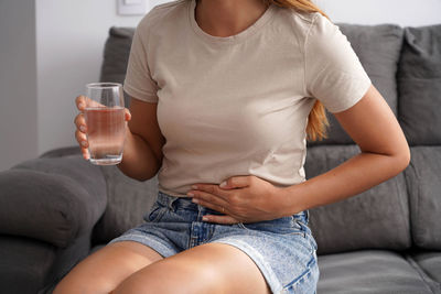 Midsection of woman sitting on sofa at home