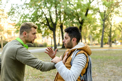 Side view of friends arguing in park during autumn