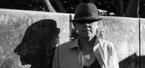 Portrait of mature woman wearing hat against wall