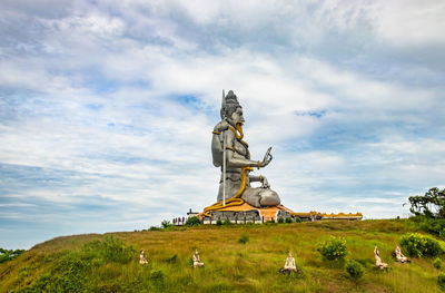 Statue of traditional windmill on landscape against sky