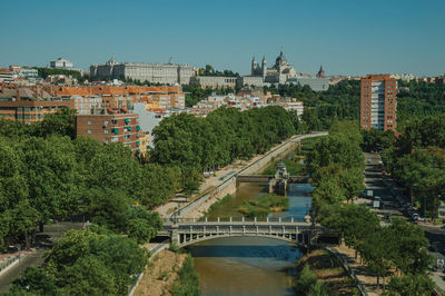 Bridge over river by buildings in city against clear sky