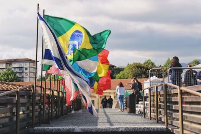 Flag by railing in city against sky
