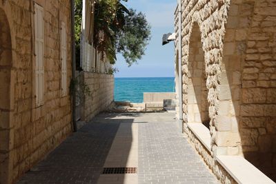 Footpath amidst buildings against sea