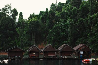 Houses by lake against trees and plants