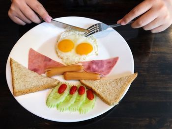 Cropped image of person holding breakfast served on table