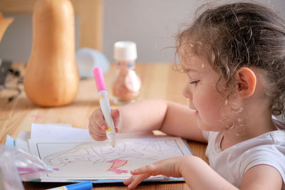 Little girl playing with invisible ink and coloring book