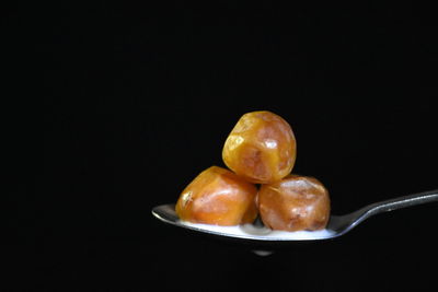 Close-up of fruits in plate on table against black background