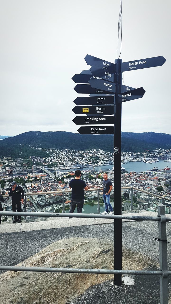 PEOPLE ON ROAD BY BUILDINGS IN CITY AGAINST SKY