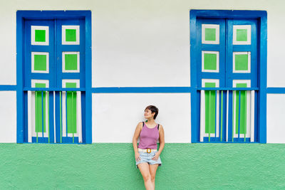 Full length of young woman standing against wall