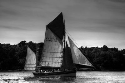 Sailboat sailing on river against sky