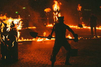 Men throwing dirt in fire at night