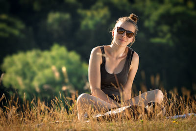 Young woman wearing sunglasses sitting on field