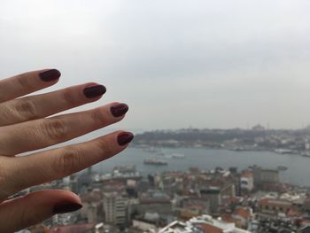 Midsection of person holding cityscape against sky