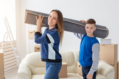 Portrait of mother and son carrying carpet
