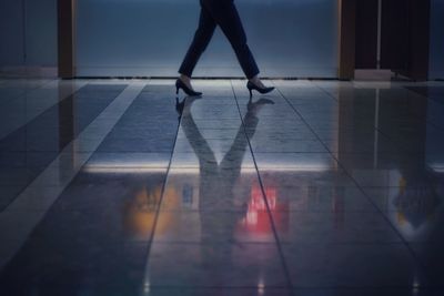 Low section of woman walking on tiled floor