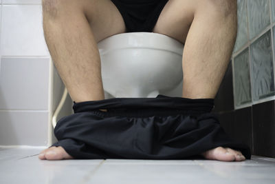 Low section of man sitting in bathroom