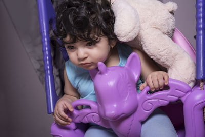 Cute girl holding toy while sitting at home