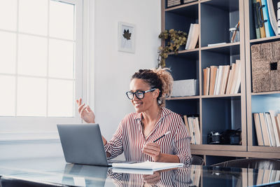 Woman using phone while sitting on table