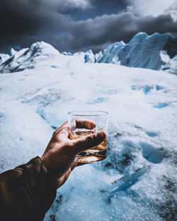 Close-up of hand holding ice cream in snow