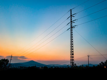 Low angle view of silhouette electricity pylon against sky during sunset